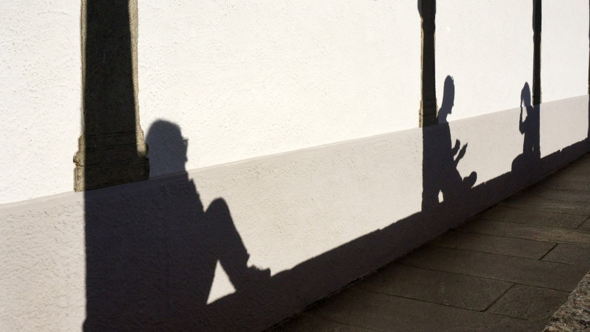 Schatten von Menschen, die sich ausruhen an eine Hauswand geworfen.