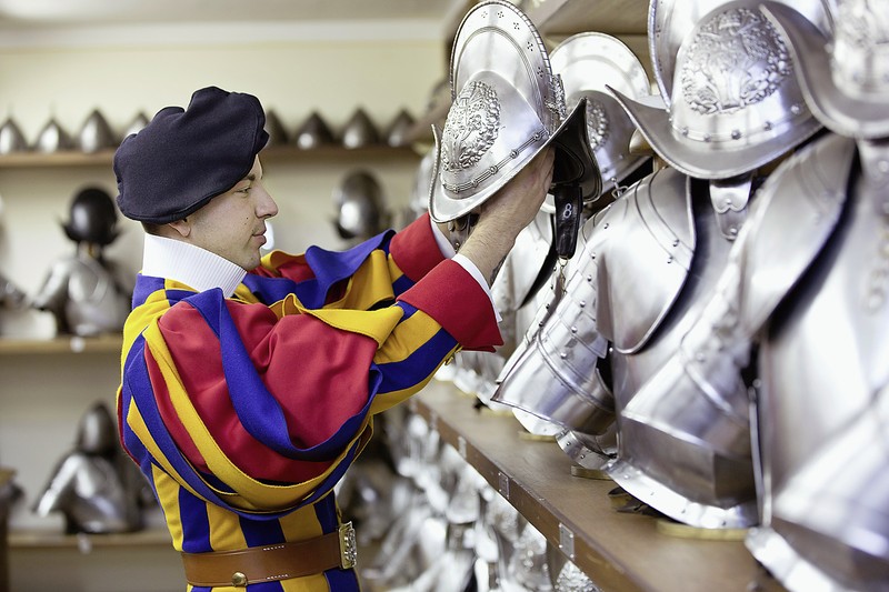 Schweizergardist in Uniform nimmt einen der Helme.