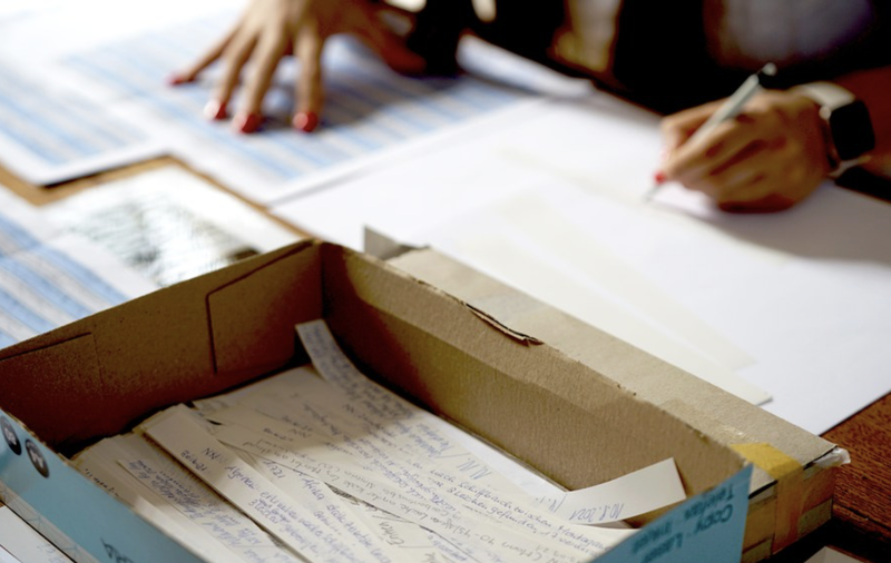 Namen von verstorbenen Menschen auf der Flucht werden auf Papierstreifen geschrieben.