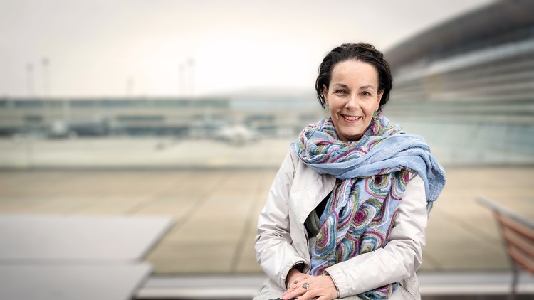 Andrea Thali lächelt in die Kamera, im Hintergrund ist der Flughafen zu sehen