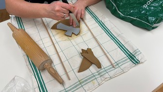 Arbeit mit Ton, Hände die ein Kreuz ausschneiden